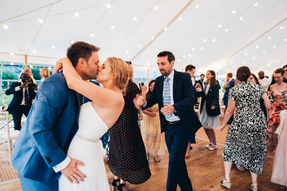 Candid moment of fun bride and groom first kiss after their first dance at marquee wedding at Humble by Nature Monmouthshire wedding photography